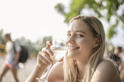 Portrait of a smiling young woman drinking glass