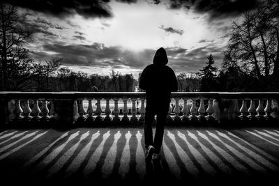 Rear view of silhouette man standing against railing