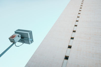 Low angle view of telephone pole against building against clear sky