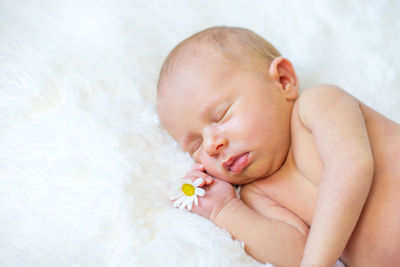 Cute baby with flower sleeping on bed at home