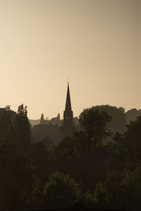 Silhouette trees and building against sky during sunset