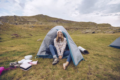 Young woman sitting in tent on mountain around ibones of anayet