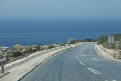 Road leading towards sea against blue sky