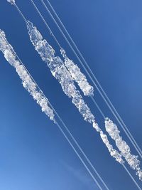 Low angle view of icicles against clear blue sky