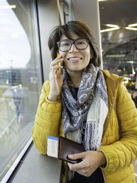 Woman with passport, boarding pass talks on smartphone. tourist is waiting for boarding at airport.