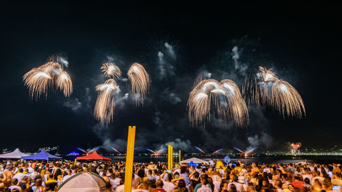 Crowd watching firework display at night