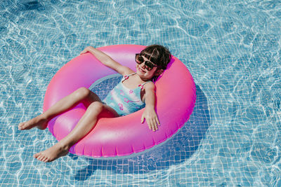 High angle portrait of smiling relaxing on inflatable ring in swimming pool