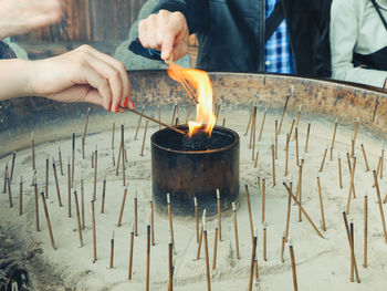 Midsection of person holding lit candles in temple