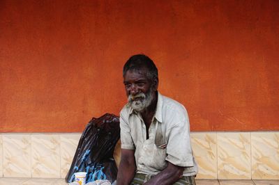 Portrait of man sitting against wall