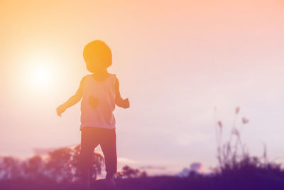 Full length of girl standing on field against sky during sunset