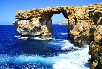 Rock formation in sea against sky