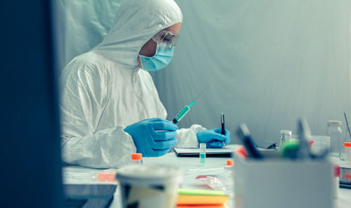 Scientist in protective suit working over chemical at laboratory