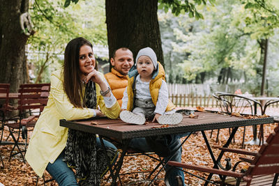 Happy friends sitting on table at park