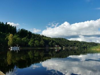 Scenic view of lake by trees against sky