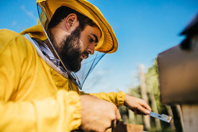 Side view of young man holding yellow camera