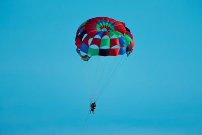 Low angle view of person paragliding against clear blue sky