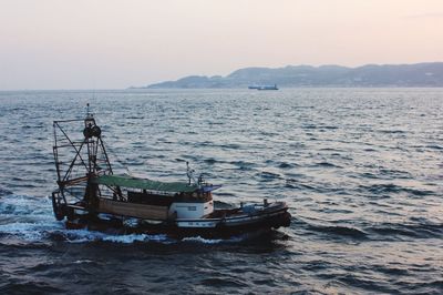 Boat sailing in sea against sky during sunset