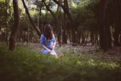 Full length of woman standing on field in forest