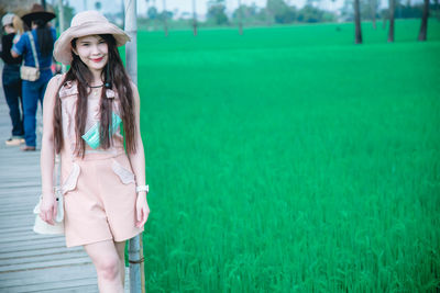 Portrait of woman wearing hat standing in grass