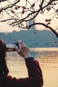 Close-up of person photographing against sky during sunset