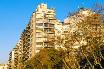 Low angle view of buildings in city against clear blue sky