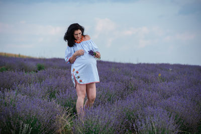 Full length of woman standing on field against sky