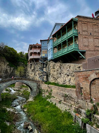 Old bridge amidst buildings in city against sky