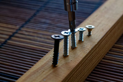 High angle view of screwdriver fixing nail in wood