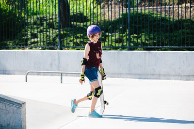 Skater girl walks with her skateboard at the skatepark
