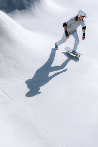 Man with helmet skateboarding in park on sunny day