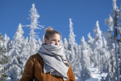 Woman standing in snow against trees during winter