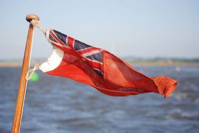 Close-up of flag by sea against sky