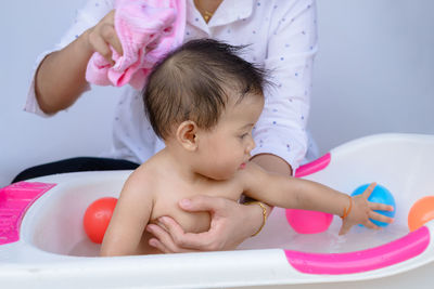 Midsection of mother holding baby girl in bathtub