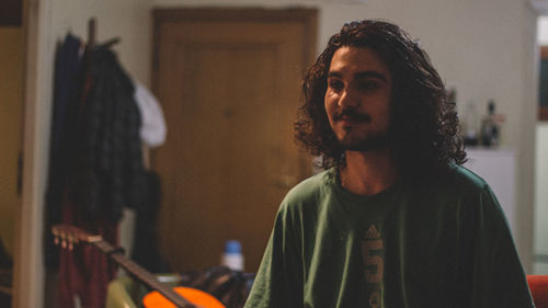 Young man looking away in room at home