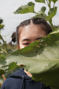 Close-up portrait of boy with leaves in plant