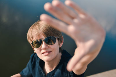 High angle portrait of mid adult woman wearing sunglasses showing stop sign