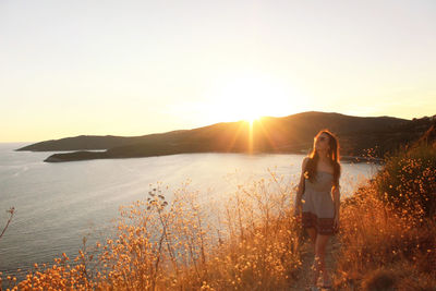 Rear view of woman standing at sunset