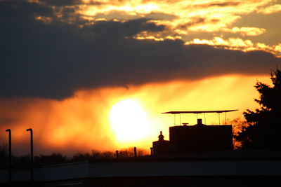 Silhouette of buildings against cloudy sky during sunset