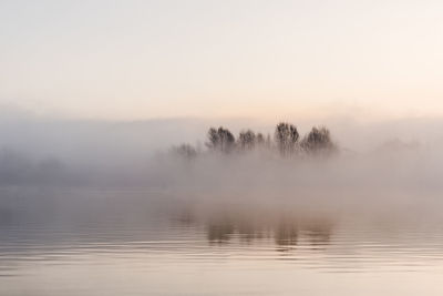 Scenic view of lake against sky during foggy weather