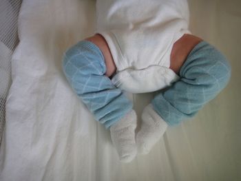 Low section of toddler baby lying on bed at home