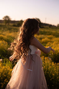 Woman standing on field against sky during sunset