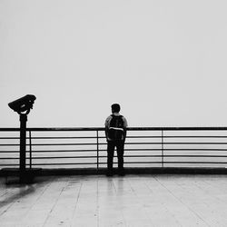 Rear view of man standing on pier over sea