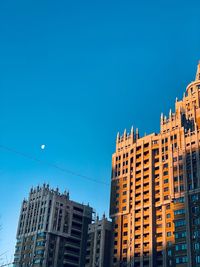 Low angle view of buildings against clear blue sky