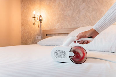 Cropped hands of woman using mobile phone on bed at home