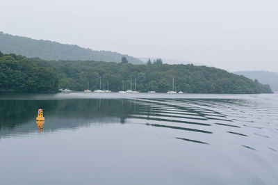 Yellow buoy in lake against sky