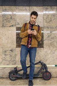 Young man checking his telephone with electric scooter in the underground