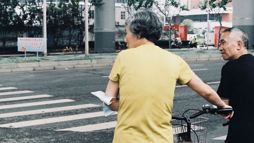 Rear view of man with umbrella on street in city