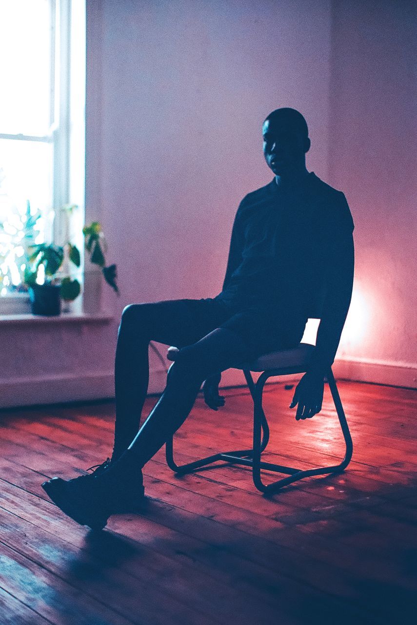 sitting, one person, indoors, adult, full length, seat, lifestyles, home interior, chair, flooring, young adult, men, performance art, window, furniture