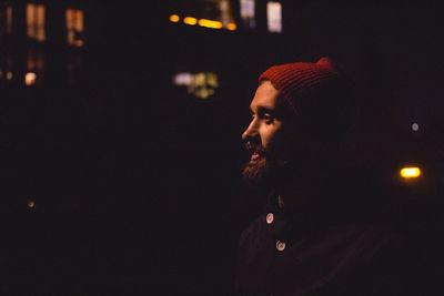 Bearded man wearing red knit hat at night