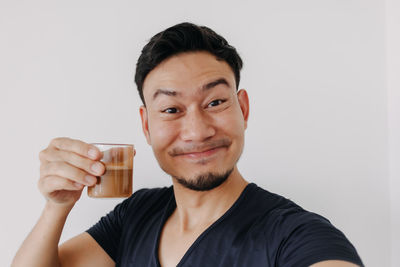 Portrait of young man using mobile phone against white background